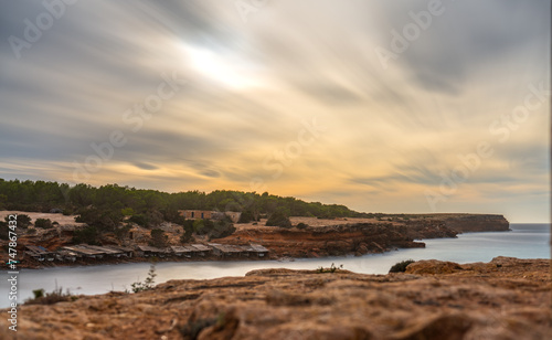 Long exposure of a cove in Formentera with fishermen's boats and cotton clouds