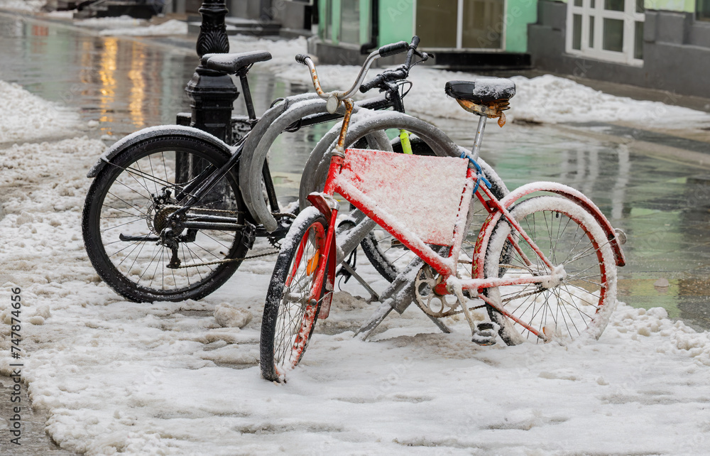 Two old bicycles parked on a city street in winter