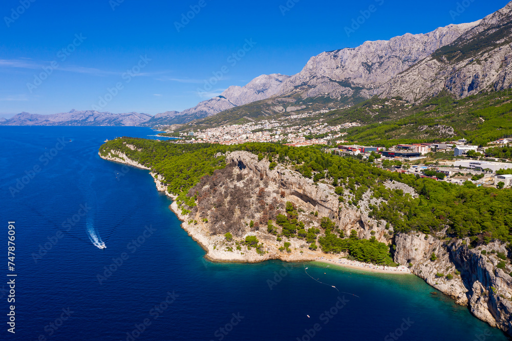 Aerial photography. Beautiful coastline, a passing boat from a bird's eye view near the city of Makarska, Dalmatia, Croatia. Makarska Riviera, famous and tourist place in Europe