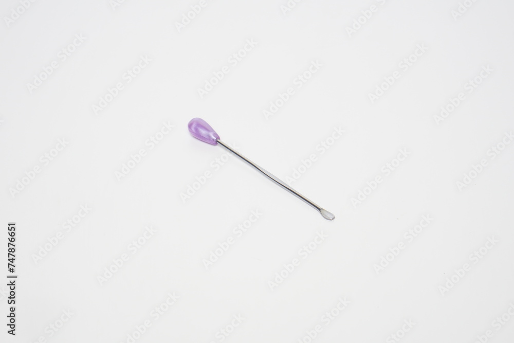 ear pick made of stainless steel with a purple plastic handle from the side angle on a white background ear pick made of stainless steel with a purple plastic handle from the side angle on a white background