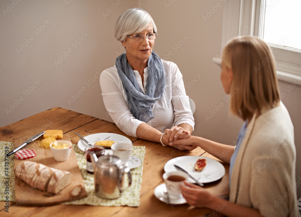 Senior mom, daughter and home with conversation in table for bonding, support and visit. Holding hands, family and meal with tea, food and chat on breakfast together with care, smile and love Senior mom, daughter and home with conversation in table for bonding, support and visit. Holding hands, family and meal with tea, food and chat on breakfast together with care, smile and love