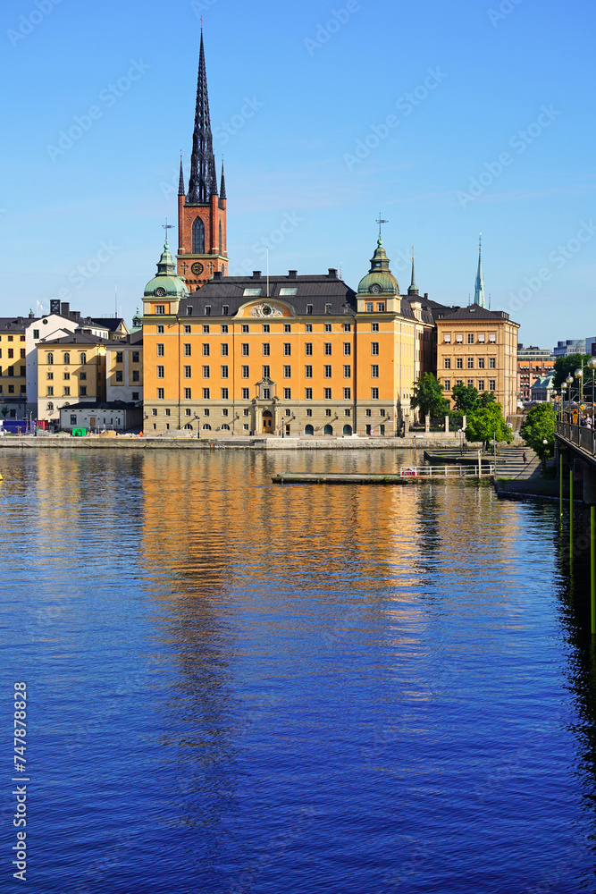 Riddarholm Church spires and typical sweden colorful gothic buildings on Lake Malaren water from Kungsholmen with blue clear sky, Stockholm, Sweden