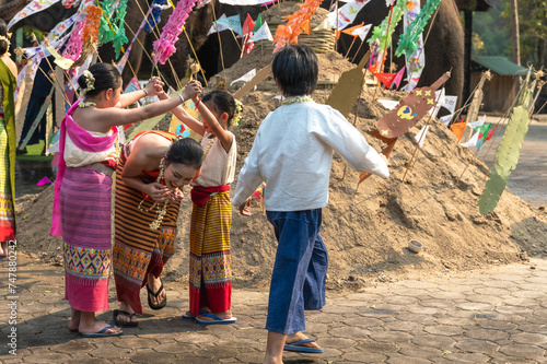 Boy and girls in traditional Thai clothing playing together at sand castle during Song kran festival in Chiangmai, Thailand
