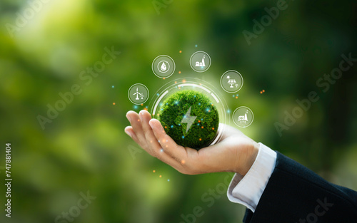 Renewable, green energy and save energy. Ecology, Sustainable clean industrial factories, hand holding a Green Globe with renewable energy sources icon, and green electricity concept. photo