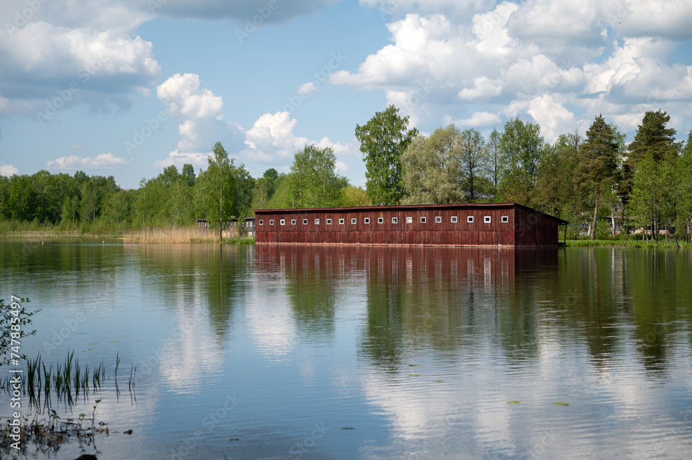 Wooden boathouse on the bank of the lake with reflection in water Wooden boathouse on the bank of the lake with reflection in water