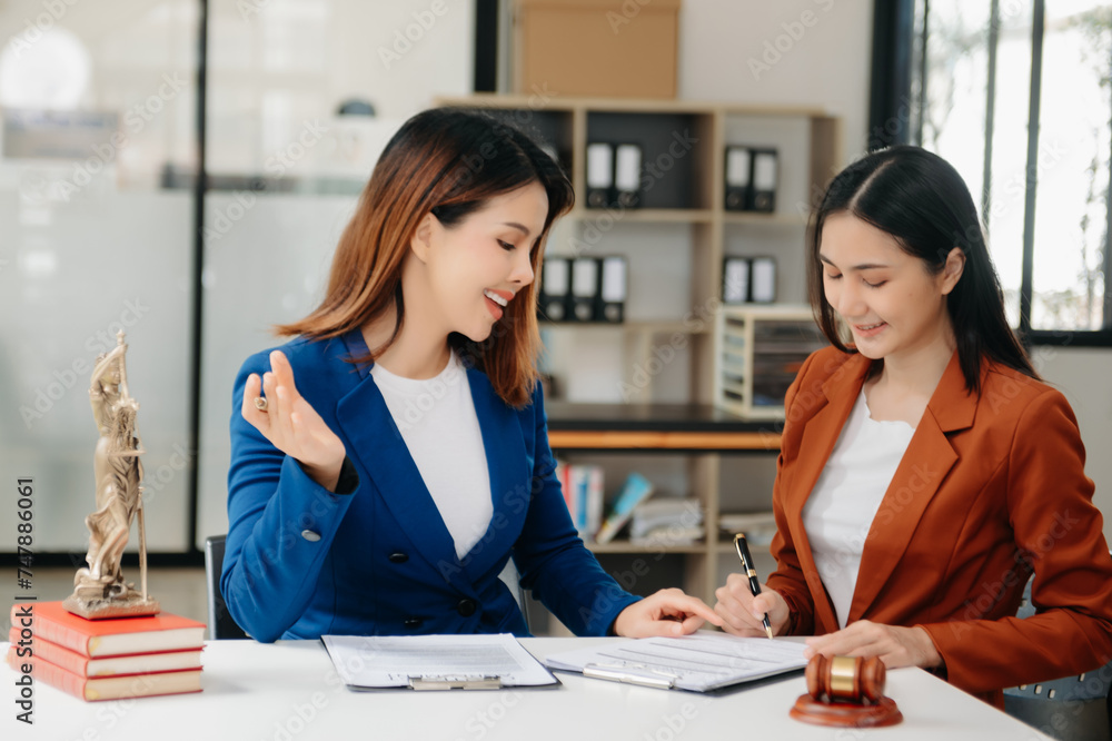 Fototapeta premium Asian Business and lawyers discussing contract papers with brass scale on desk in office. Law, legal services, advice, justice and law concept .