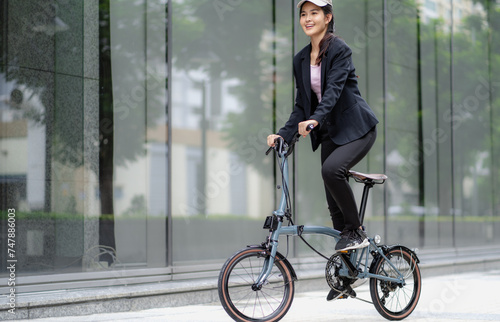 Confident 20s businesswoman ride bicycle outside to office in downtown. Environmentalist commuting by cycling reduce carbon footprint. Bike to work eco friendly alternative vehicle to global warming.