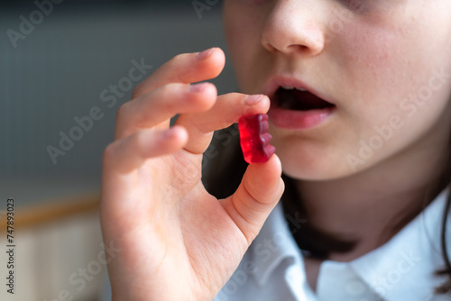 Child Girl Eating Gummy Bear Candy: Close-Up