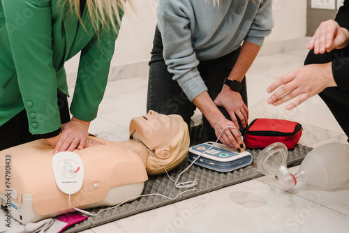 Automated external defibrillator device, AED with training dummy mannequin. Use an automatic defibrillator in conducting basic cardiopulmonary resuscitation of victim. Demonstrating chest compressions photo