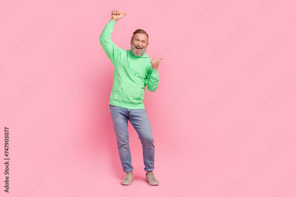 Full size photo of cool pensioner man point cheerful empty space dressed stylish green clothes isolated on pink color background Full size photo of cool pensioner man point cheerful empty space dressed stylish green clothes isolated on pink color background