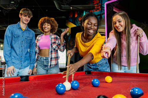 Fotografie group of multiethnic friends having fun playing billiards aiming at the balls