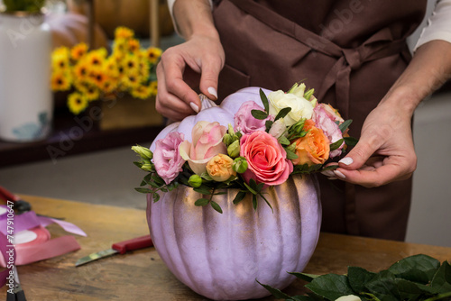 Florist makes an arrangement of pumpkins and flowers