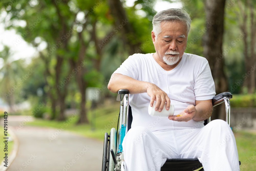 senior man sitting on wheelchair and taking medicine in the park senior man sitting on wheelchair and taking medicine in the park