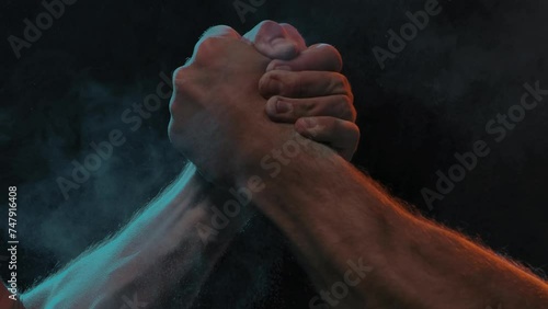 Sporty handshake of two muscular men on black background photo