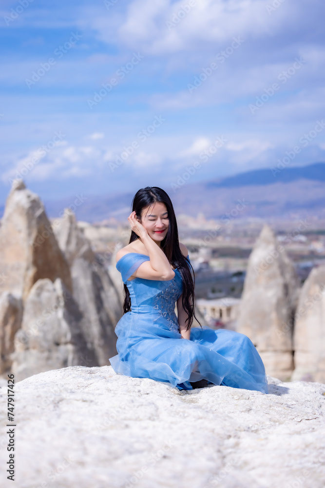 Beautiful woman in blue dress on rocks mountain. Cheerful woman relax outdoor with beautiful sky and pink flowers in holiday vacation. Woman tourist enjoy amazing mountain view. Travel and freedom.. Beautiful woman in blue dress on rocks mountain. Cheerful woman relax outdoor with beautiful sky and pink flowers in holiday vacation. Woman tourist enjoy amazing mountain view. Travel and freedom..
