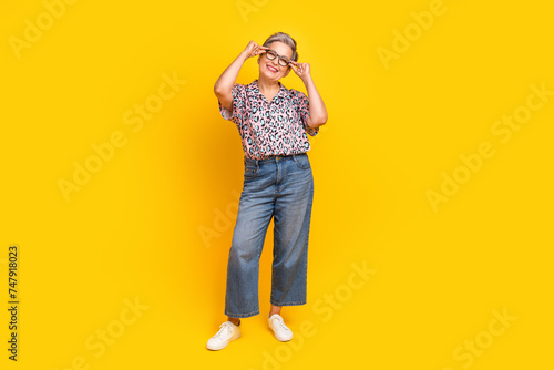 Full body photo of attractive pensioner woman touch specs cheerful wear trendy leopard print clothes isolated on yellow color background