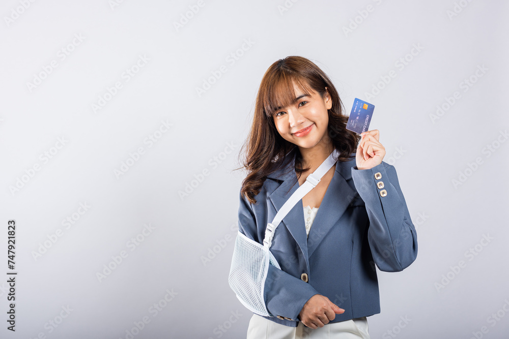 Woman confident smile broken arm after accident and wear arm splint for treatment she emergency pay medical bills by credit card, Happy Asian female sling support hand isolated on white background Woman confident smile broken arm after accident and wear arm splint for treatment she emergency pay medical bills by credit card, Happy Asian female sling support hand isolated on white background