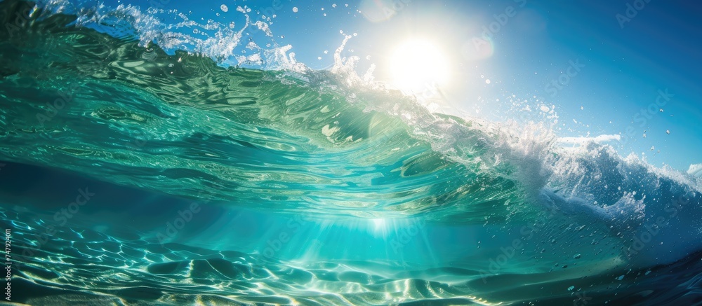 The sun shines brightly over the clear ocean waves during summertime, reflecting its rays on the surface and under the blue waters, creating a stunning sight.