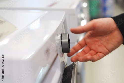 A white man's hand adjusts the knob on a washing machine