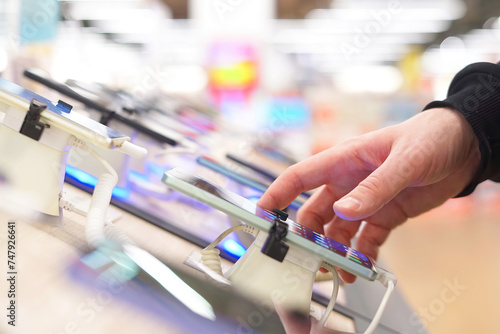 Hand of male buyer testing smartphone in electronics store