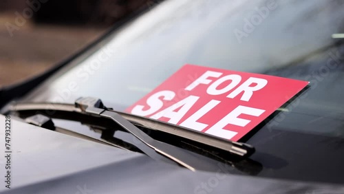 Close up of man placing car for sale sign board in front of car. Men putting his car up for sale.