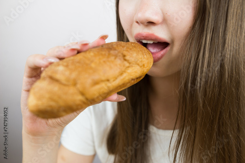 young beautiful girl eating a croissant  close-up  crop photo. female mouth eating croissant