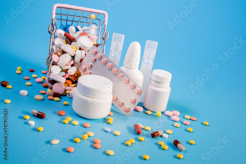 Buy and shopping medicine concept. Various capsules, tablets and medicine in the shopping cartt on a blue background. Creative idea for health care, health insurance and pharmaceutical company. photo