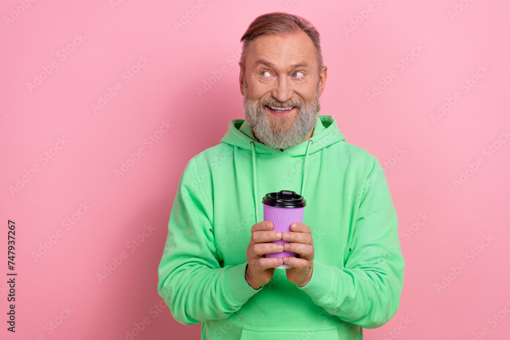 Photo of cheerful funny man wear green sweatshirt drinking tea looking empty space isolated pink color background Photo of cheerful funny man wear green sweatshirt drinking tea looking empty space isolated pink color background