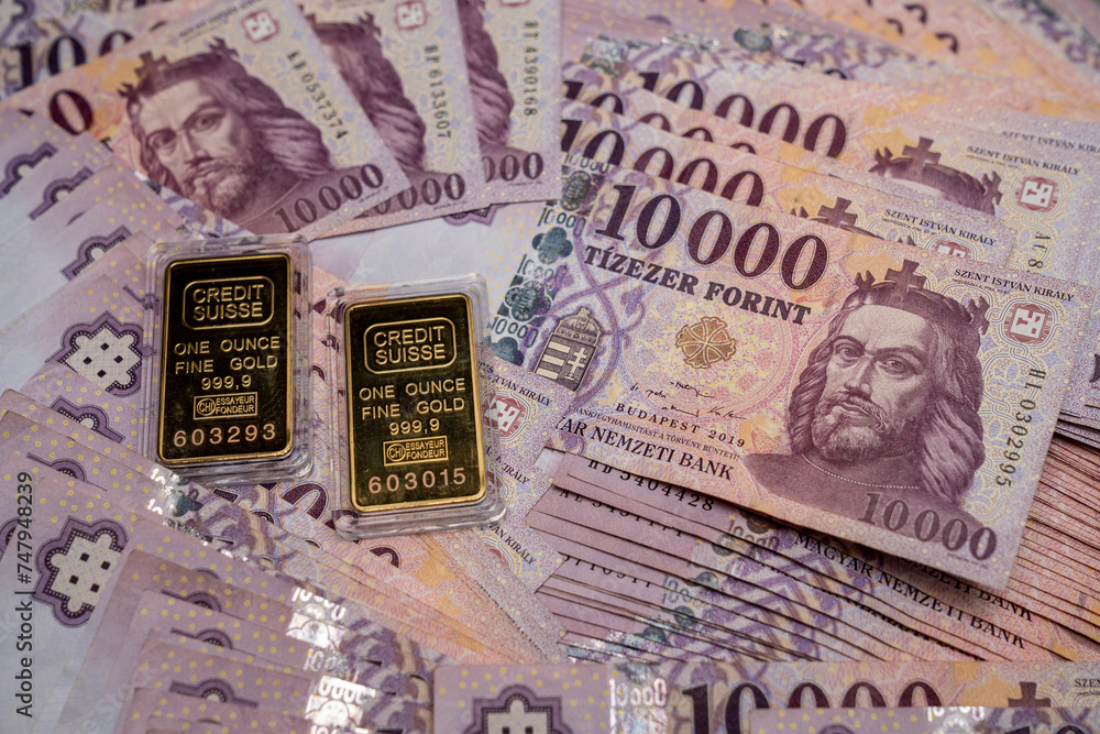 The Hungarian 10,000 forint banknotes are scattered and spread out on the table. With gold bars next to it. Large denominations, Inflation and financial situation in Hungary.