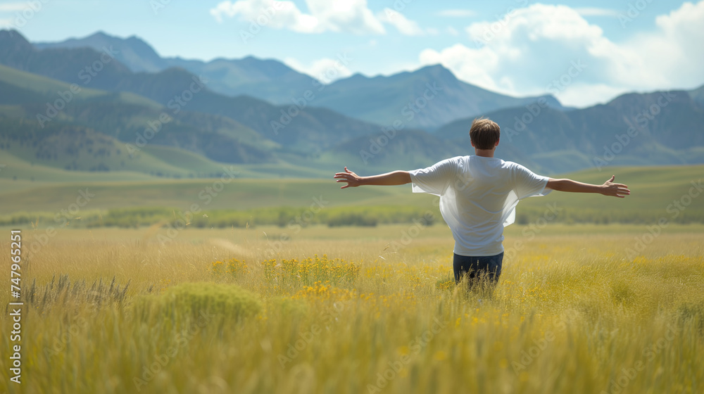 A man stands with open arms in a golden meadow, with the majestic mountains in the background under a clear sky. A man stands with open arms in a golden meadow, with the majestic mountains in the background under a clear sky.