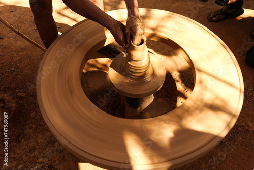 Man makes a pot by help of the wheel. photo