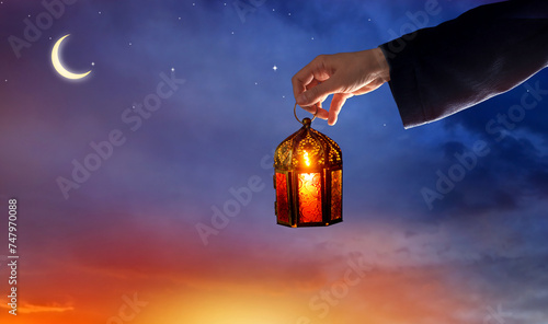 Hand holding  Arabic Ramadan Lantern. Decoration lamp. Crescent moon and the stars. Islamic greeting Eid Mubarak cards for Muslim Holidays.Eid-Ul-Adha festival celebration