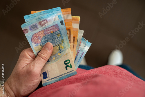 A man holds money in his hand. Cash in euros for payment or exchange. The man counts the payment in euro banknotes. Saving money, taking a bank deposit. European money. Financial crisis.