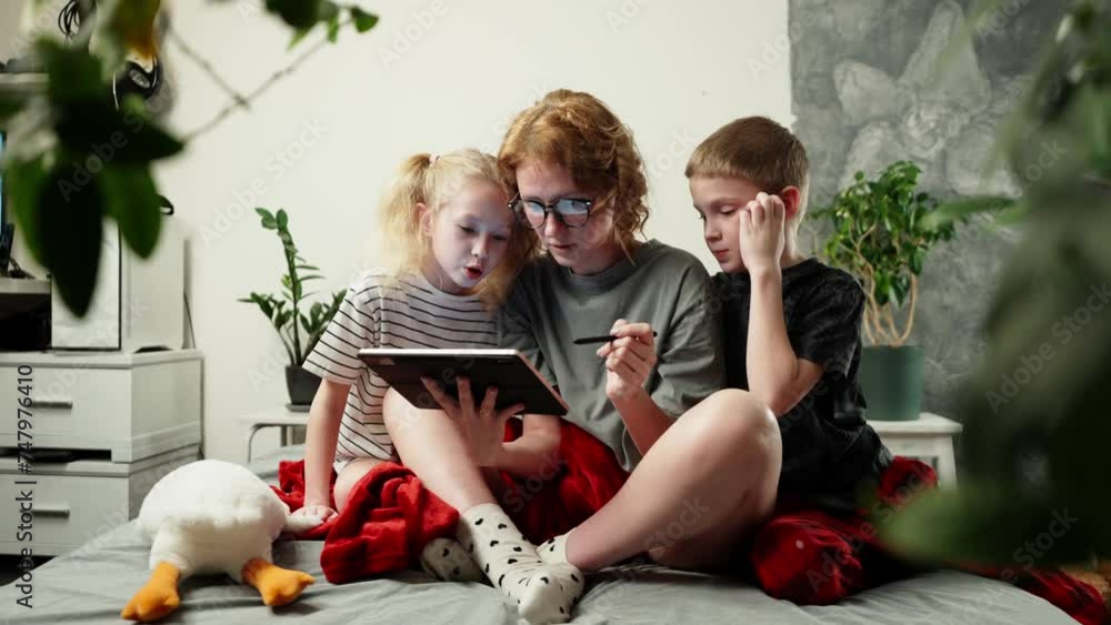 Mom shows children interesting educational videos on a tablet at home in a comfortable environment on a soft sofa. Mom shows children interesting educational videos on a tablet at home in a comfortable environment on a soft sofa.