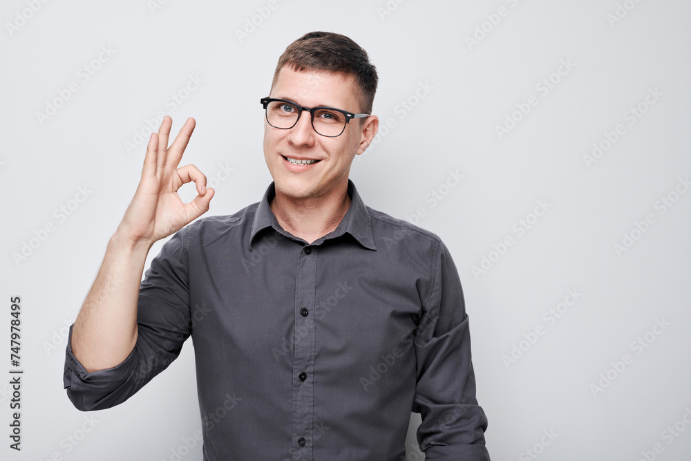 Cheerful man in checkered shirt making OK gesture, smiling at camera on white background Cheerful man in checkered shirt making OK gesture, smiling at camera on white background