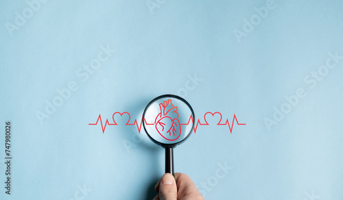 Magnifying glass over heart with electrocardiograms, life insurance heart care concept, world heart day