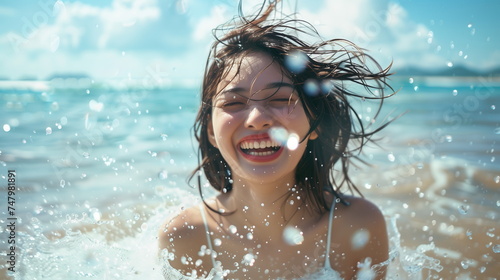 ビーチで水遊びをしてはしゃぐ日本人の若い女性