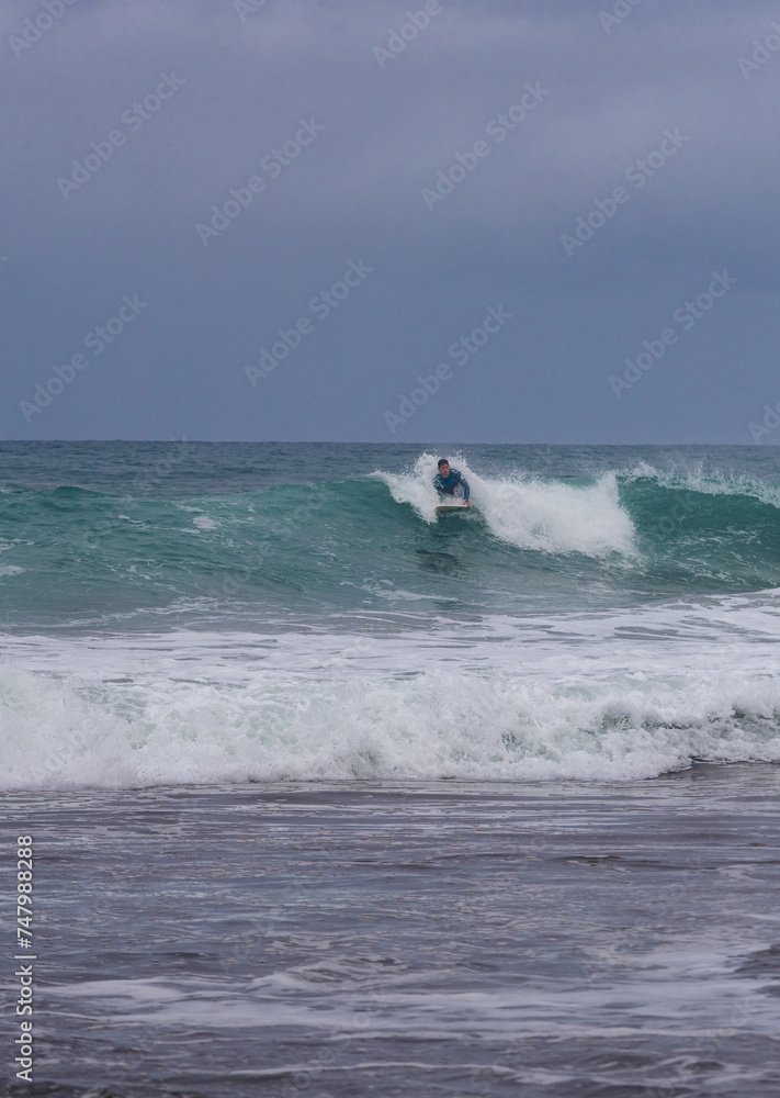 Surfer riding wave in overcast weather, copy space. Surfer riding wave in overcast weather, copy space.