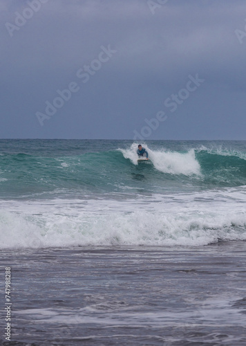 Surfer riding wave in overcast weather, copy space.