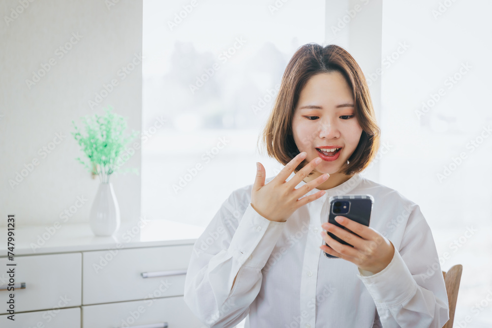 スマホを見て驚く女性 A surprised woman looking at her smartphone スマホを見て驚く女性 A surprised woman looking at her smartphone