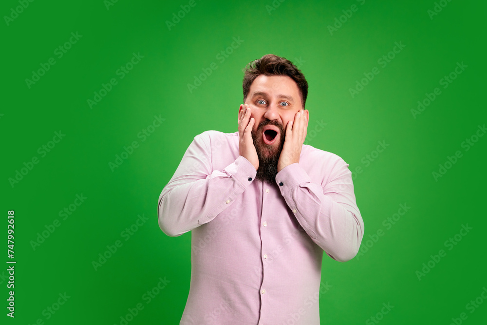 Pleasant surprised man put hands on face with wow facial-expression against vibrant green studio background. Positive emotions. Concept of self-expression, fashion, style, information, news. Ad Pleasant surprised man put hands on face with wow facial-expression against vibrant green studio background. Positive emotions. Concept of self-expression, fashion, style, information, news. Ad
