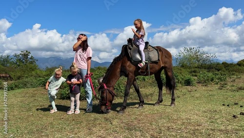 Three little sisters of triplets standing near a brown horse in summer photo