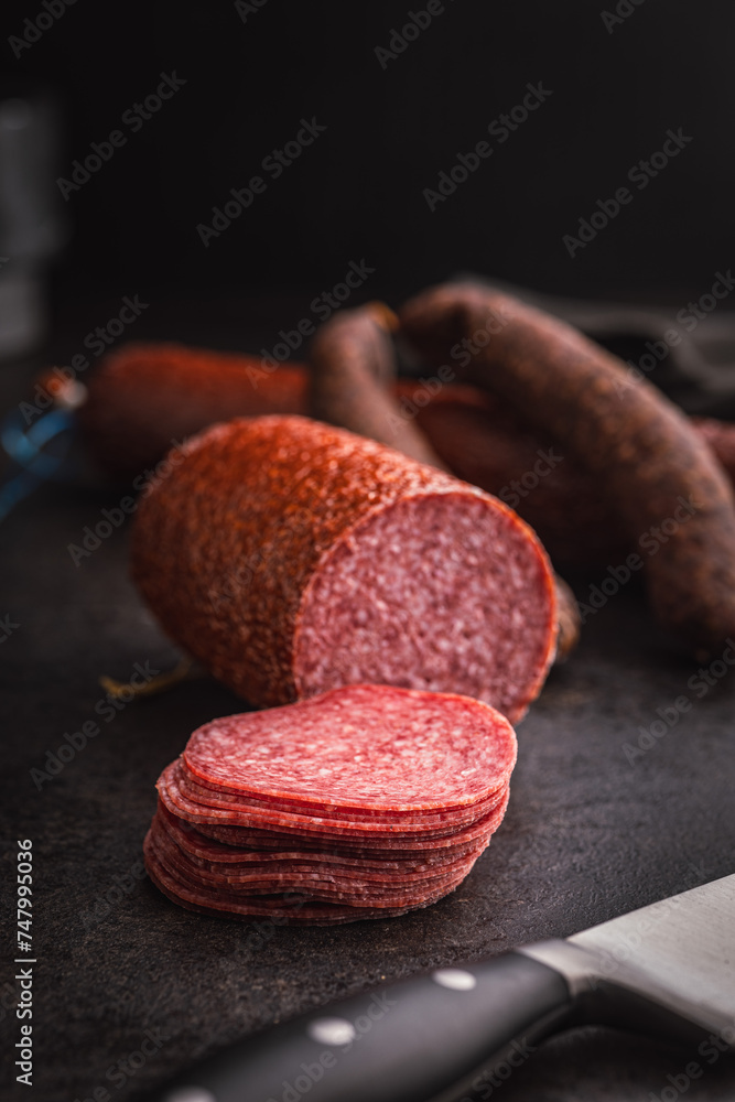Sliced smoked salami sausages on black table. Sliced smoked salami sausages on black table.