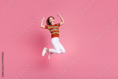 Full length portrait of delighted nice person jumping raise fists accomplish empty space isolated on pink color background photo