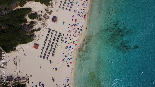 Cala agulla beach with vibrant umbrellas, clear water, and parked cars, aerial view photo