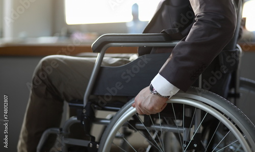 Close-up of disabled man on wheelchair in office wearing presentable suit. Adaptation of people with disabilities in society. Recovery and healthcare concept