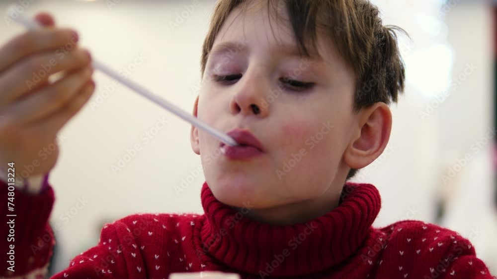 portrait of a smiling Caucasian boy in a sweater eating dessert in a cafe. a child drinks a cocktail while in a children's cafe. family time in cafe portrait of a smiling Caucasian boy in a sweater eating dessert in a cafe. a child drinks a cocktail while in a children's cafe. family time in cafe