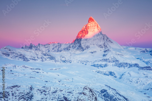 First sunrays on the snowy peak of Matterhorn mountain  with pink sky at sunrise in the Swiss Alps