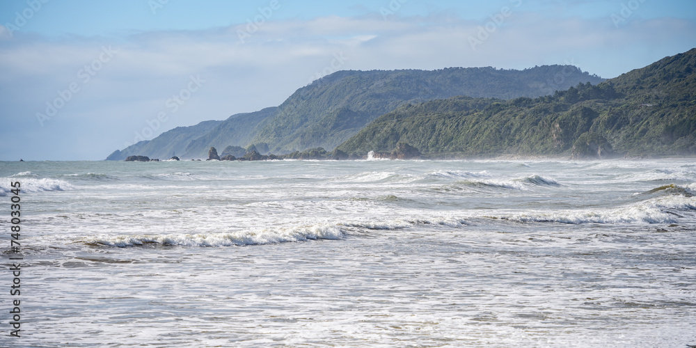 Rough exotic coastal landscape with big waves and rainforest vegetation on a sunny day, New Zealand