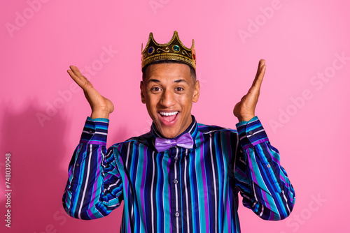 Photo of funky impressed guy wear striped shirt golden crown rising arms hands isolated pink color background